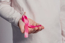 hand holding out a pink ribbon 