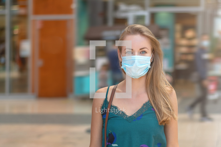 Urban city lifestyle. Young beautiful woman with face mask in modern shopping mall.