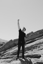 man standing on a mountaintop with a raised fist 