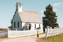 child running towards a small white church 