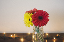 gerber daisies in a mason jar on a wooden table 