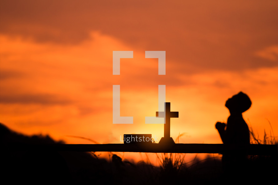 silhouette of a boy praying at sunset 