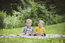 brothers sitting on a blanket in the grass