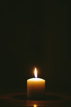 flame on a white candle in darkness 