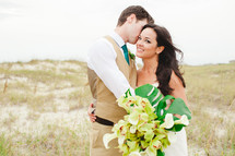 a bride and groom with sand dunes in the background 