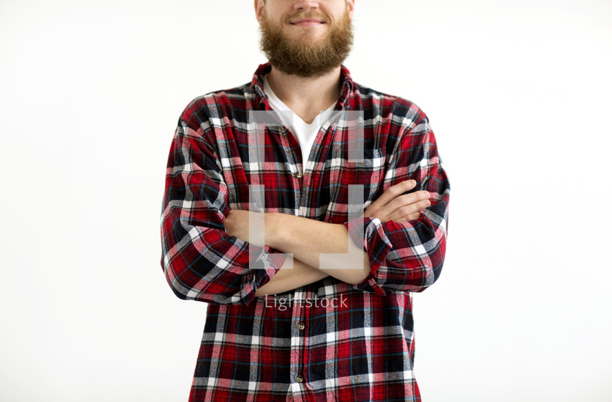 a man in a plaid flannel shirt with arms crossed