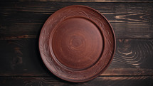 Empty ukrainian clay plate from wooden table. Top view. National tableware with handmade ornament