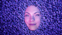 Smiling woman face in fresh ripe blueberries. Young attractive girl covered with acai berries. Lady with bright makeup. enjoying organic bilberry plant. Diet, antioxidant, healthy vegan food.