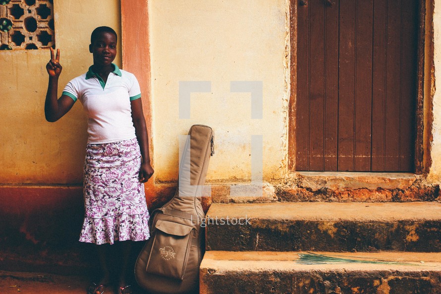 A woman standing next to a guitar case 