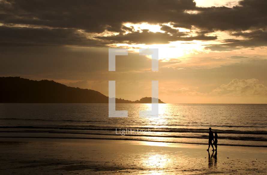 couple walking on a beach at sunset 
