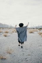 a woman walking in a desert and view of wind turbines 
