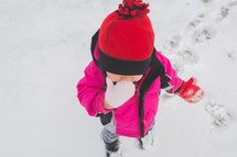 a toddler girl standing in snow 