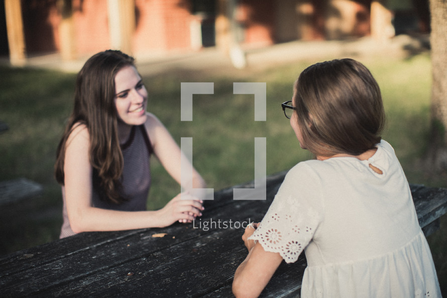teen girls talking sitting at a picnic table 