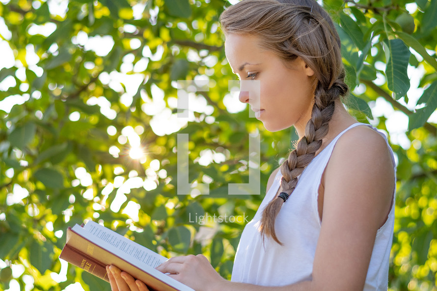 a woman reading a Bible outdoors 
