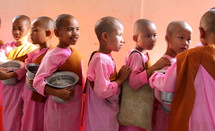 Buddhist novice monks in traditional pink dress carrying begging bowls