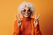 Cheerful african american woman in sunglasses showing peace signs on orange background