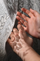 sunlight on a child's hands through the lace curtains 