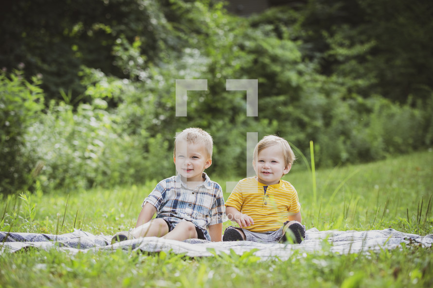 brothers sitting on a blanket in the grass