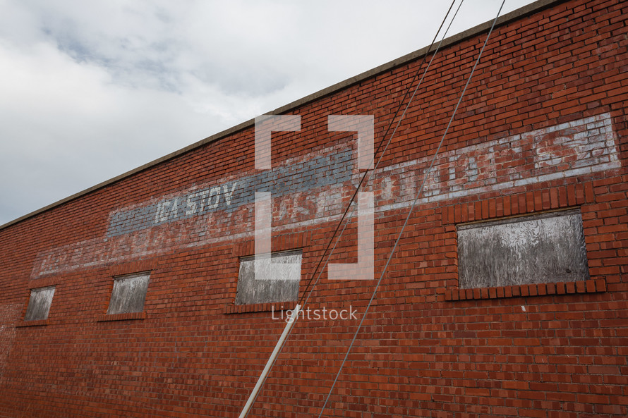 Worn sign for grocery store on red brick