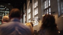 A group of people sit in church pews during a catholic ceremony or mass on a Sunday morning.