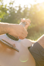 man strumming a guitar in warm sunlight 