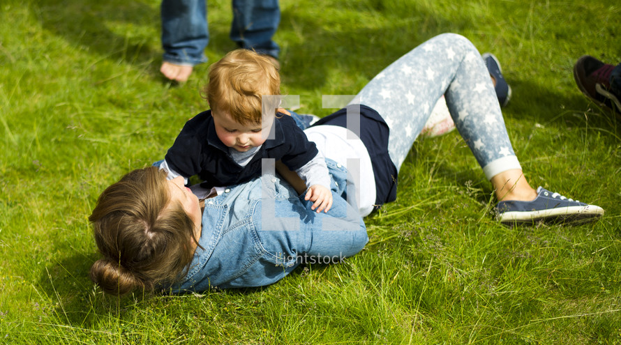 Mother holding her toddler son in the grass.