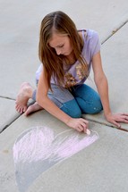 girl drawing a heart on a sidewalk 