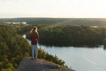 a woman looking down at a lake taking in the view 