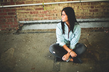a woman sitting on a sidewalk 