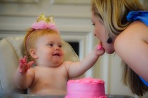a baby feeding mom birthday cake on her first birthday 