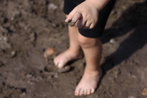 toddler standing in mud 