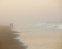 people walking on a beach in fog 