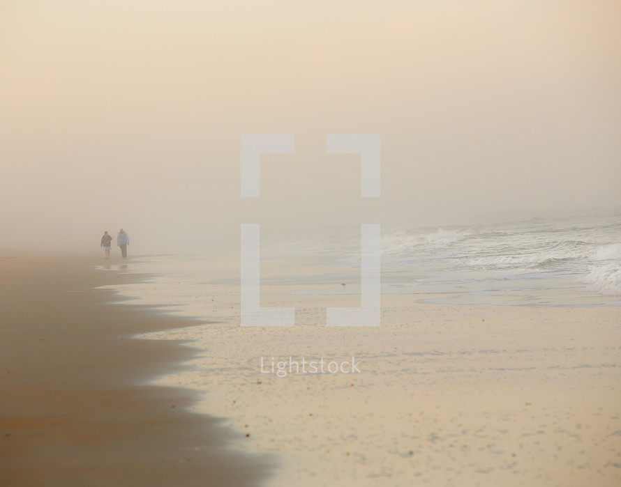 people walking on a beach in fog 