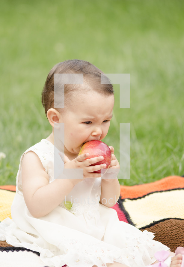 ittle girl eating a red apple