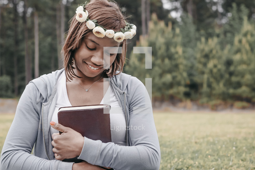 a woman with flowers in her hair holding a Bible 