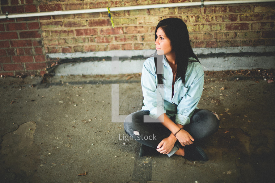 a woman sitting on a sidewalk 