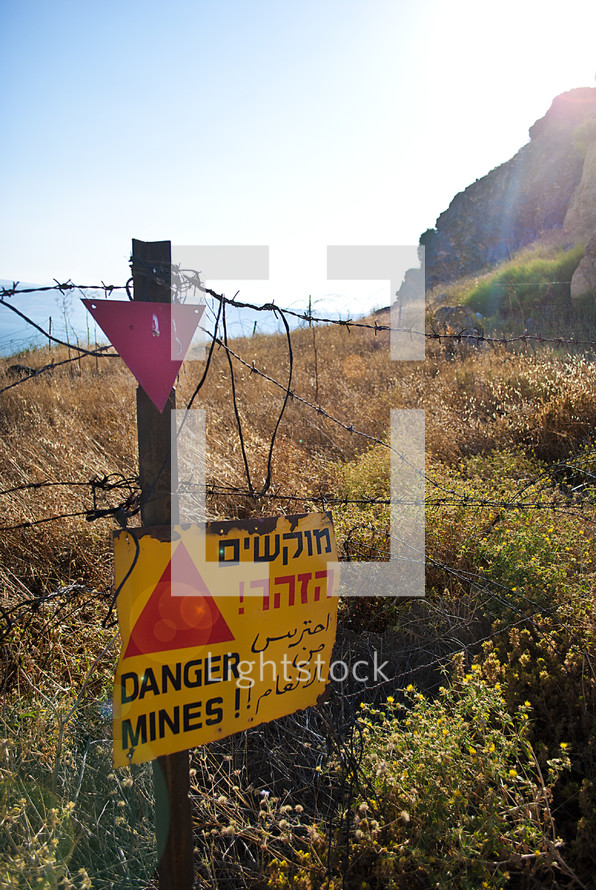 A barbed wire fence with a danger sign.