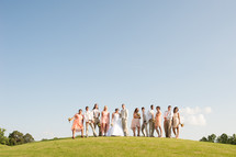 Wedding party standing on a hill outside.