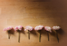 A row of pink flowers on a wooden table.