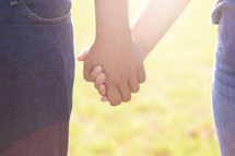 A Young Man and Woman Holding Hands Outside in the Sun