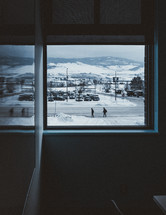 view of a snowy parking lot out of a window 