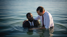 Baptism. A white Pastor baptize a black man in the water