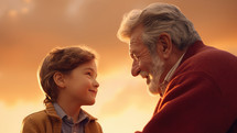 Grandfather and grandson looking at each other and smiling at sunset sky