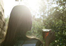 Woman with cup of tea in evening sunlight