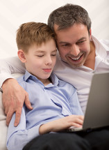 Happy dad and son with laptop at home