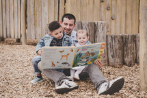 father reading a book to his kids 
