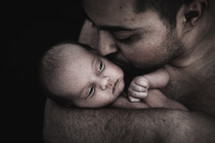 father kissing a newborn 