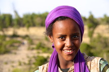smiling woman wearing a purple scarf on her head 