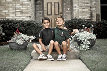 brothers sitting on a sidewalk together