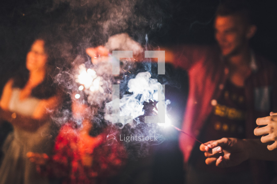 holding sparklers outdoors at night 